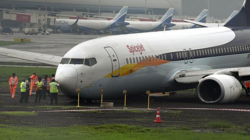 A SpiceJet aircraft is surrounded by airport staff as it stands stranded off the tarmac at Chhatrapati Shivaji Maharaj International Airport in Mumbai on July 2, 2019, after it overran the runway while landing during heavy rain, causing no injuries. AFP