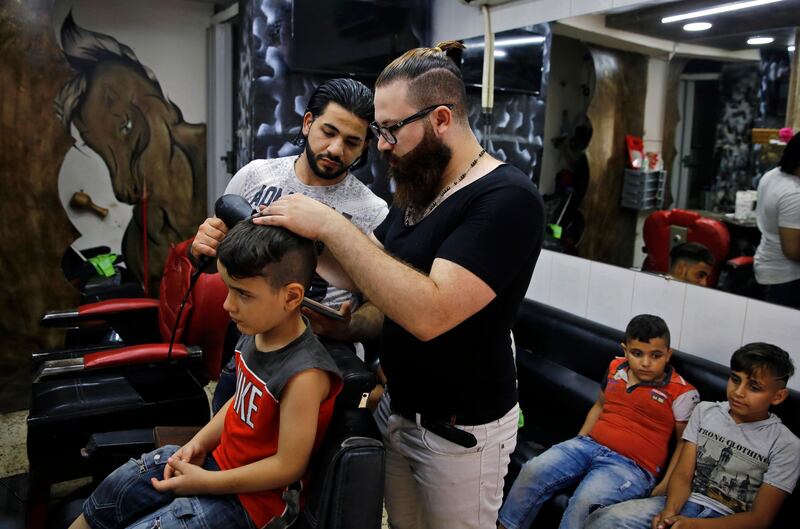 
                  In this Friday, July 14, 2017 photo, Muhannad Khaled Omar, right, prepares to create an image of U.S. President Donald Trump on the back of a customer's head at his barber shop in Burj al-Barajneh, southern Beirut, Lebanon. In a city full of hair stylists, Omar stands out. He is a 26 year-old Palestinian-Syrian hair stylist known for shaving celebrity portraits into clients’ hair. (AP Photo/Bilal Hussein)
               