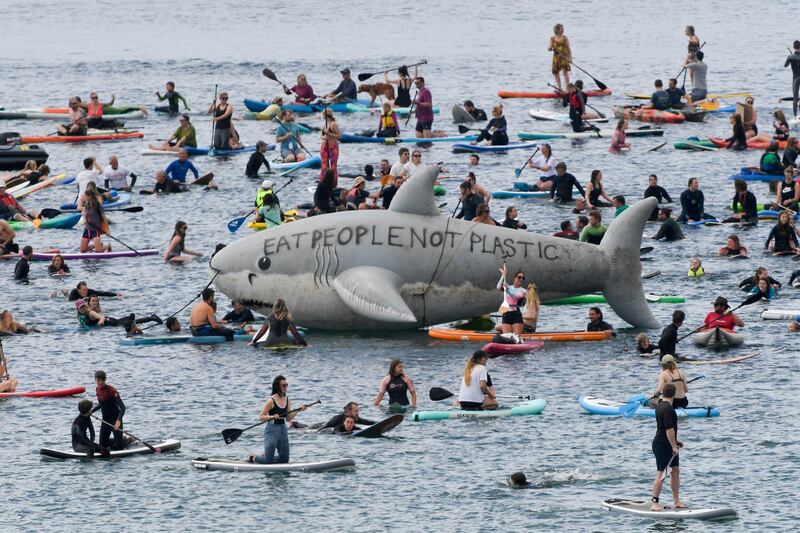 People ride kayaks and boards around a prop shark in a protest in Gyllyngvase beach, Falmouth. Reuters