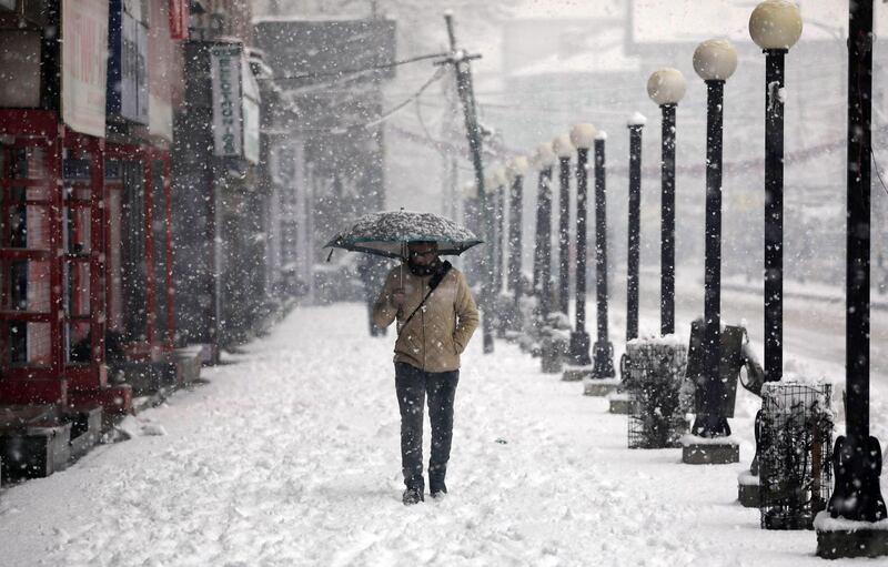 A Kashmiri man holds an umbrella to protect himself from snow as he walks during fresh snowfall in Srinagar, the summer capital of Indian Kashmir. EPA