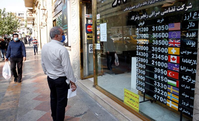 An Iranian man checks the currency rate as he walks past a currency exchange service in Tehran, Iran.   EPA