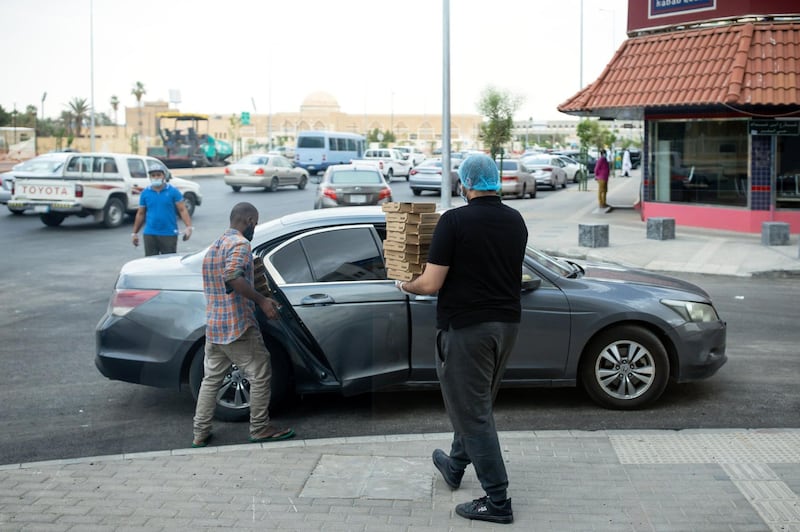An employee carries pizzas in boxes for delivery to customers outside a Maestro Pizza food store in Riyadh, Saudi Arabia, on Tuesday, May 19, 2020. Hit simultaneously by plunging crude prices and coronavirus shutdowns, the non-oil economy is expected to contract for the first time in over 30 years. Photographer: Tasneem Alsultan/Bloomberg