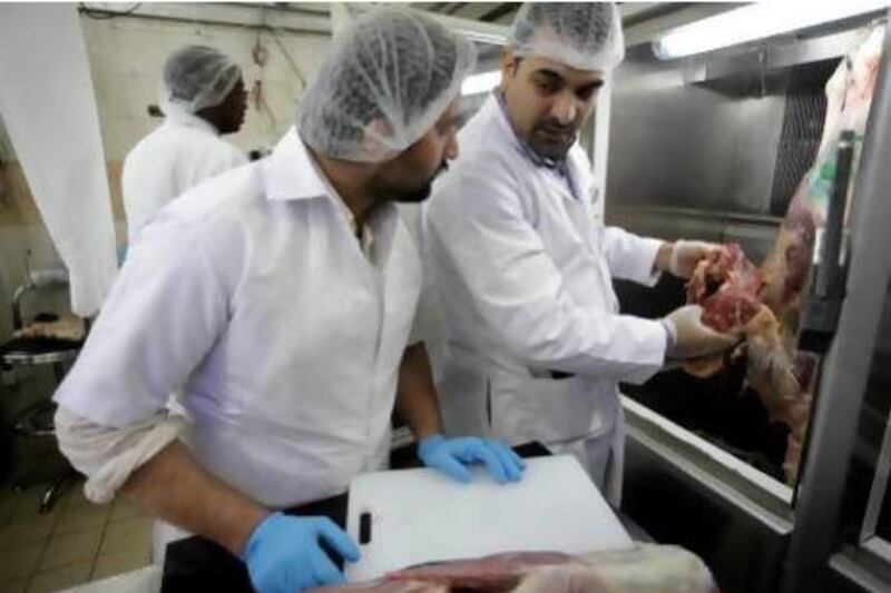 Faris Issa with the Abu Dhabi Food Control Authority, right, inspects meat at the Al Manzoor Butchery. Sammy Dallal / The National