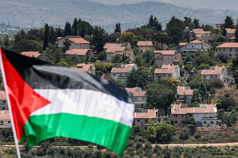 The Israeli settlement of Halamish behind a Palestinian flag raised for the funeral of Mohammed Haitham Al Tamimi, a three-year-old Palestinian boy shot by Israeli forces in the occupied West Bank. AFP