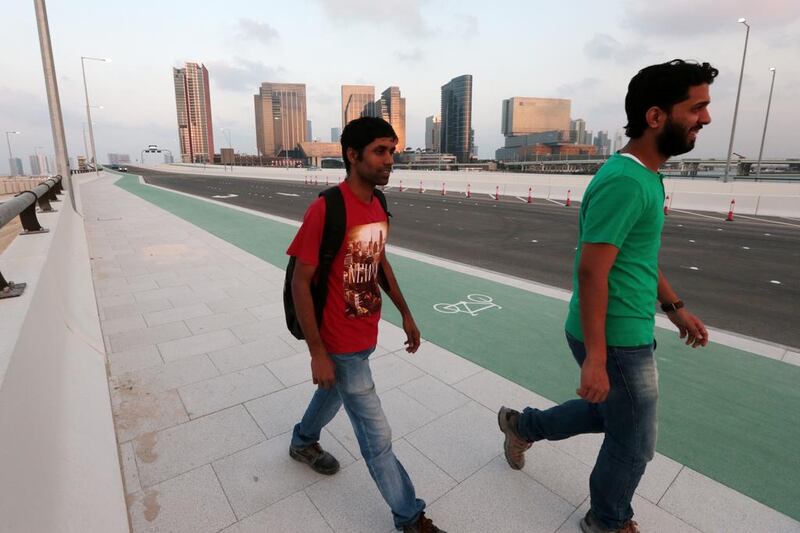 Two men walk across one of the two newly opened bridges connecting Al Maryah Island to the tourist club area in Abu Dhabi. Christopher Pike / The National