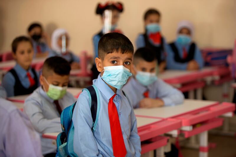 Students wear face masks in their classroom, in Baghdad, Iraq, Monday, Nov.  1, 2021.  Across Iraq, students returned to classrooms Monday for the first time in a year and a half – a stoppage caused by the coronavirus pandemic - amid overcrowding and confusion about COVID-19 safety measures.  (AP Photo / Hadi Mizban)