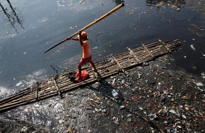 A worker gathers plastic and other debris from the Sekretaris River in Jakarta, Indonesia. Darren Whiteside / Reuters