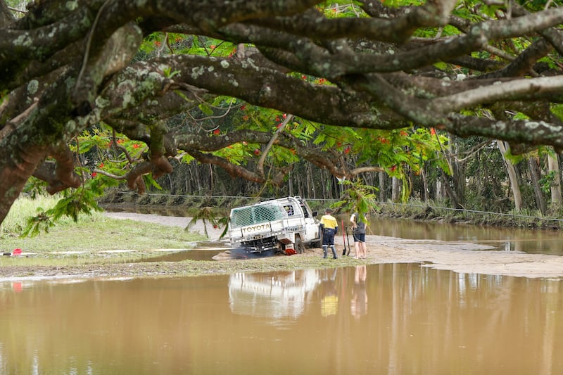 People attempt to rescue a vehicle bogged in mud from the receding floodwaters in Cairns, Australia, on Monday. EPA