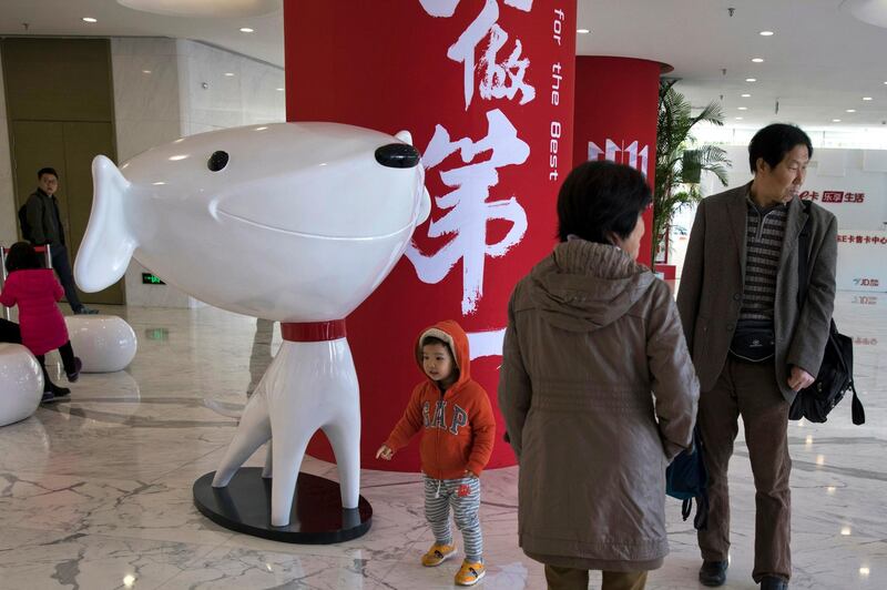 In this Nov. 11, 2017, photo, a child stands near the mascot for Chinese e-commerce giant JD.com and the words for "Be Number One" at the headquarters in Beijing, China. Google says Monday, June 18, 2018, it will invest $550 million in Alibaba's main rival JD.com as the U.S. tech giant seeks to expand in fast-growing Asian e-commerce markets. (AP Photo/Ng Han Guan)