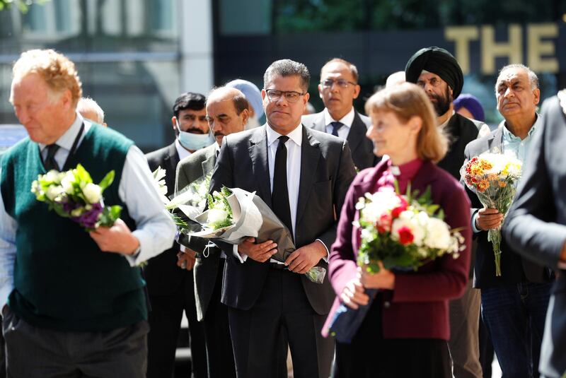 Britain's Secretary of State for Business, Energy and Industrial Strategy, Alok Sharma, holds flowers to place them near to the scene of reported multiple stabbings, as he is surrounded by faith leaders, in Reading, Britain, June 22, 2020. REUTERS