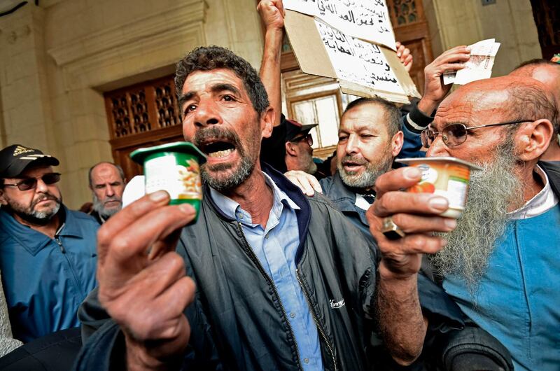 Algerian men lift yoghurt pots, symbols of former prime minister Ahmed Ouyahya, as they wait at the main public entrance of Sidi M’hamed court in the capital Algiers to attend a corruption trial of former political and business figures.  AFP