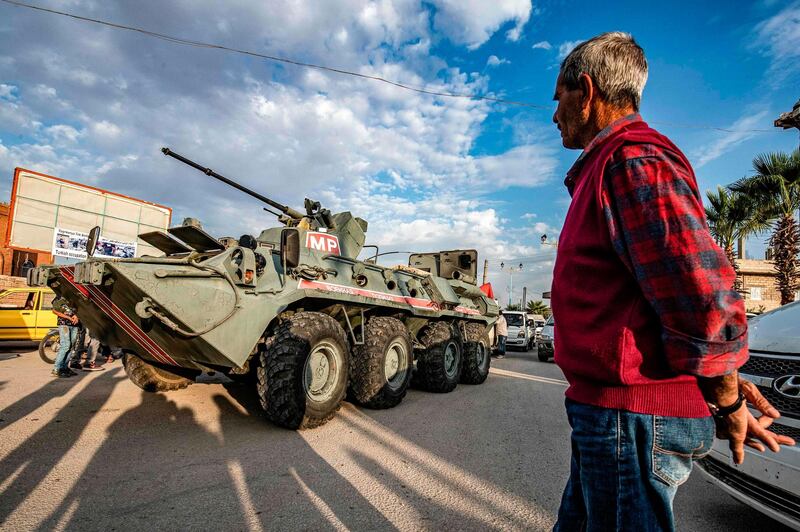 A man watches as a Russian military police armoured vehicle passes through a street in the northeastern Syrian town of Amuda. AFP