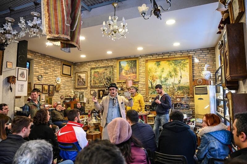 Auctioneer Ali Tuna shows items to the audience at an auction house in Istanbul's Balat district. AFP