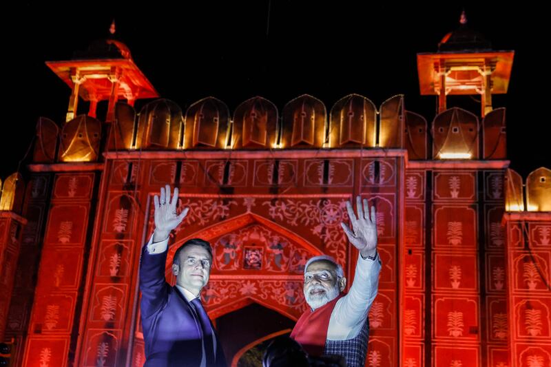 India's Prime Minister Narendra Modi (R) and France's President Emmanuel Macron wave from atop a vehicle as they at Rambagh Palace at the end of a roadshow in Jaipur on January 25, 2024. AFP