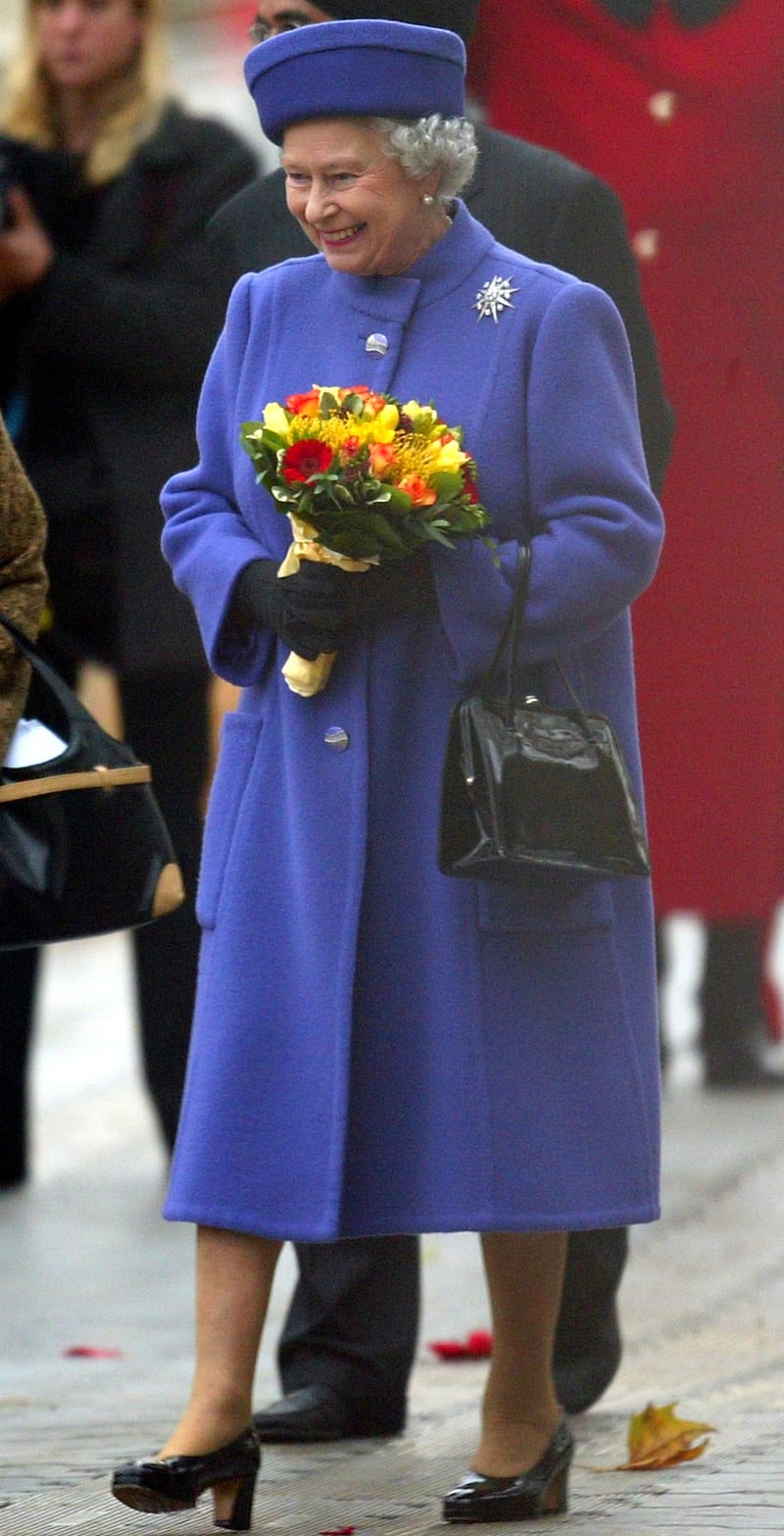 Queen Elizabeth II, wearing blue, attends the inauguration ceremony of the Memorial Gates at Constitution Hill on November 6, 2002, in London. Getty Images