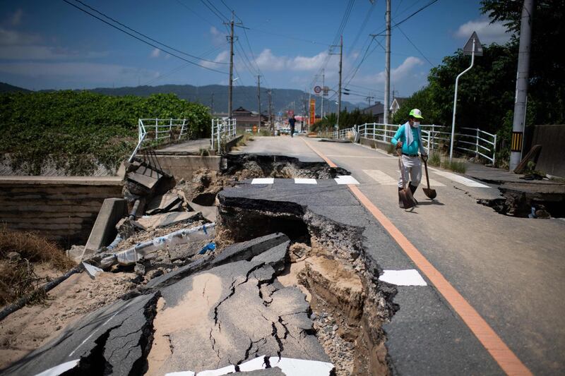 A man with a shovel walks on a damaged road in Mabi, Okayama. AFP