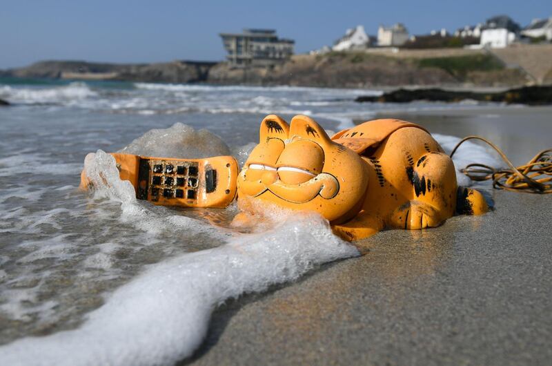 A plastic 'Garfield' phone on a beach in Le Conquet, western France. For more than 30 years, these phones have been washing up on French beaches. AFP