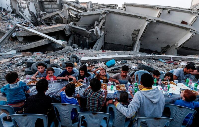 Palestinian families break their fast next to a destroyed building during recent confrontation between Hamas and Israel, in Gaza Strip on May 18, 2019, during the Muslim holy fasting month of Ramadan.  / AFP / MAHMUD HAMS
