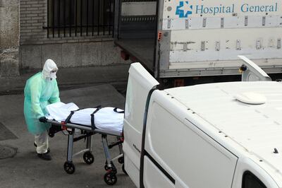 A health worker carries a body on a stretcher outside Gregorio Maranon hospital in Madrid on March 25, 2020. Spain joined Italy today in seeing its death toll from the coronavirus epidemic surpass that of China, as more than a billion Indians joined a lockdown that has confined a third of humanity. / AFP / OSCAR DEL POZO
