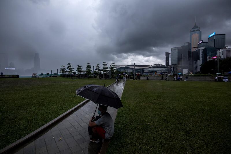 A man sits under an umbrella at Tamar Park outside the Legislative Council building a day after violent clashes over a proposed extradition bill in Hong Kong, China. Bloomberg