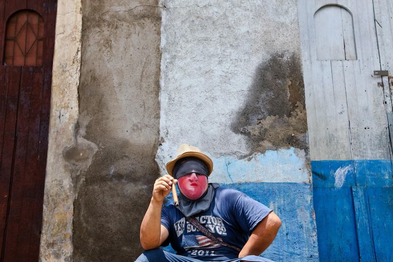 A protester wearing a mask to protect his identity smokes a cigar in the Monimbo neighborhood, in Masaya, Nicaragua. Esteban Felix / AP Photo
