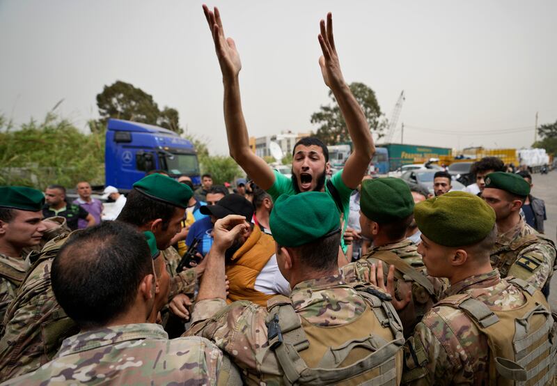 Lebanese army soldiers try to calm an angry relative of a man who is one of the missing migrants from an overnight sinking of a migrant boat, outside the seaport, in Tripoli, north Lebanon. AP