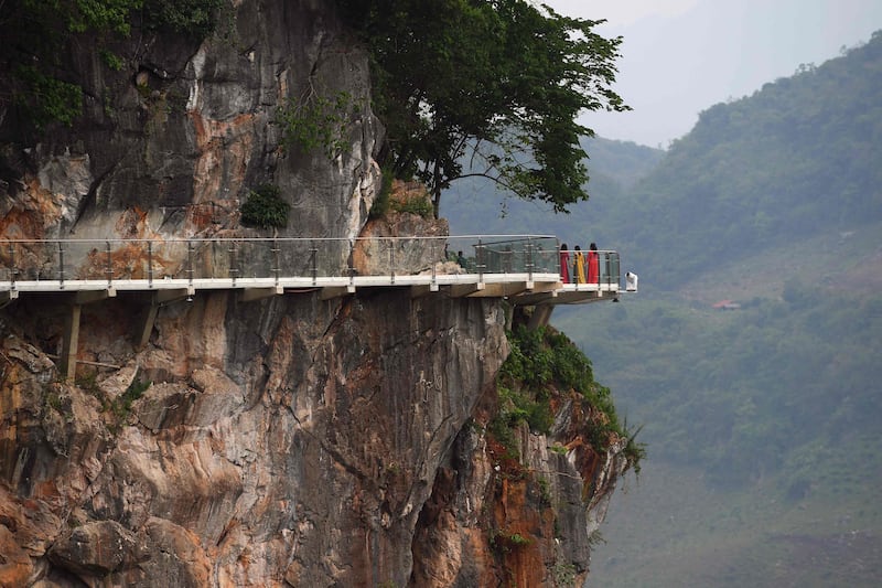 The bridge is suspended above a lush, jungle-clad gorge.