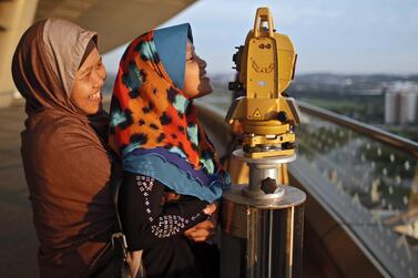 A mother holds her daughter to look at a telescope to determine the sighting of the new moon to mark the start of the fasting month of Ramadan in Putrajaya, outside Kuala Lumpur, Malaysia. Fazry Ismail / EPA