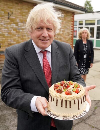 Boris Johnson holding a birthday cake presented to him by the staff during a socially distanced visit to Bovingdon Primary School in Hertfordshire on June 19, 2020. AFP