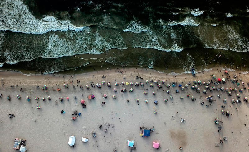 TOPSHOT - An aerial view taken on July 24, 2020, shows Palestinians sunbathing on a beach in Gaza City on a hot summer day. / AFP / MAHMUD HAMS
