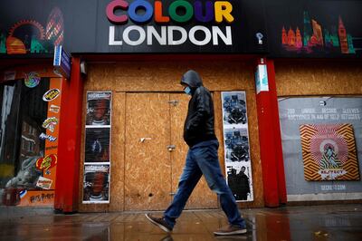 A man walks past a boarded up shop in central London on November 20, 2020, as life under a second lockdown continues in England.  The current lockdown in England has shuttered restaurants, gyms and non-essential shops and services until December 2, with hopes business could resume in time for Christmas. / AFP / Tolga Akmen
