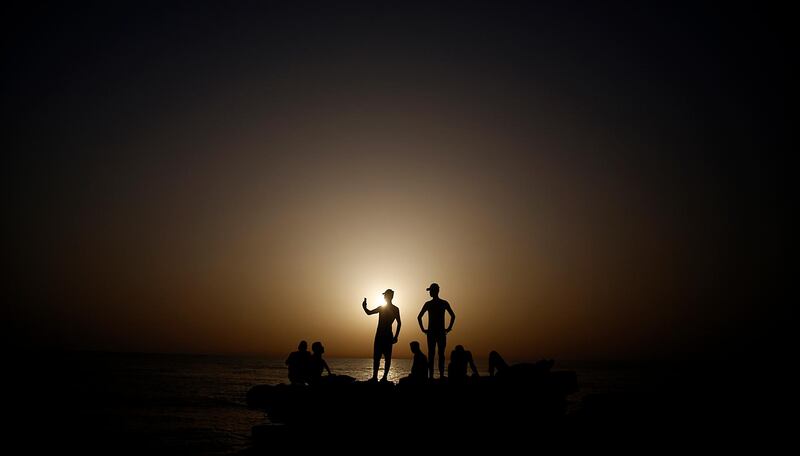 Palestinian men take pictures during sunset at the Gaza port, in Gaza City. The beach is one of the few open public spaces in this densely populated city. AP Photo