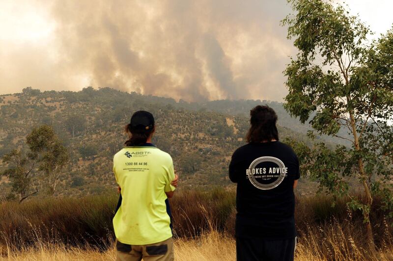 People look on as a fire driven by strong winds burns on a ridge in the suburb of Brigadoon in Perth. AFP