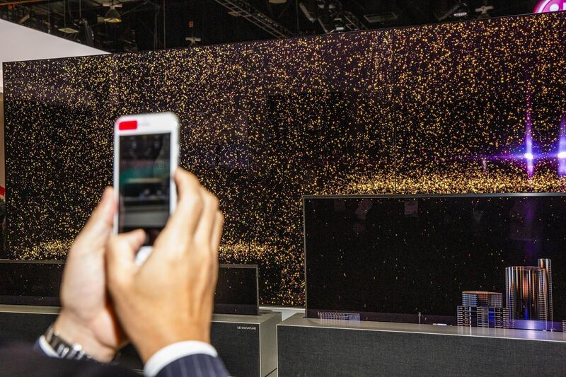 An attendee takes a video of LG Electronics Inc. Signature OLED TV R televisions at the 2019 Consumer Electronics Show (CES) in Las Vegas, Nevada, U.S., on Wednesday, Jan. 9, 2019. Dozens of companies will give presentations at the event, where attendance is expected to top 180,000, with the trade war between the U.S. and China as well as Apple's sales woes looming over the gathering. Photographer: David Williams/Bloomberg