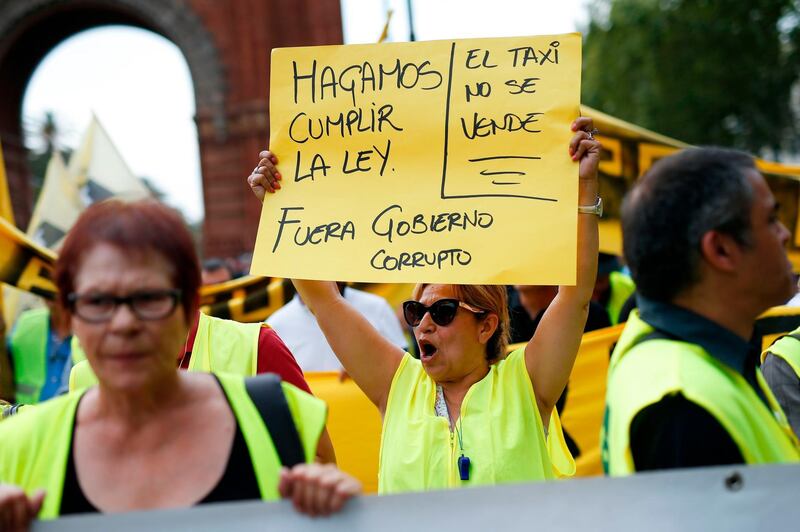 A taxi driver holds a sign reading "Let's enforce the law, taxis can not be bought. The corrupt government out!" during a strike by taxis in Barcelona.  AFP / Pau Barrena