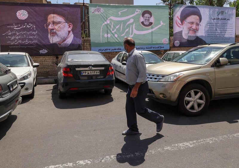 An Iranian man walks past an electoral poster depicting judiciary chief and presidential candidate Ebrahim Raisi in the capital Tehran, on May 29, 2021. Iran's presidential election campaign officially kicked off yesterday, without fanfare and in an atmosphere of indifference as many say the result is a foregone conclusion. / AFP / ATTA KENARE
