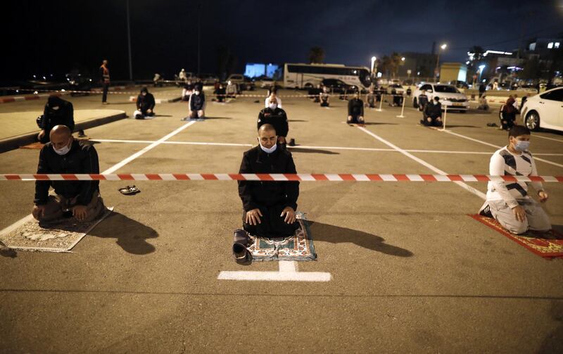 Palestinian and Arab Israeli men keep a 2-meter distance amid the COVID-19 pandemic, as they pray in a parking lot near the beach in Jaffa, near the Israeli coastal city of Tel Aviv after breaking their fast, on the second day of the Muslim holy month of Ramadan, on April 25, 2020. - Mosques stood empty and fast-breaking feasts were cancelled as Muslims around the world began marking Ramadan under the novel coronavirus lockdown, while a pushback in some countries sparked fears of a surge in infections. (Photo by Ahmad GHARABLI / AFP)