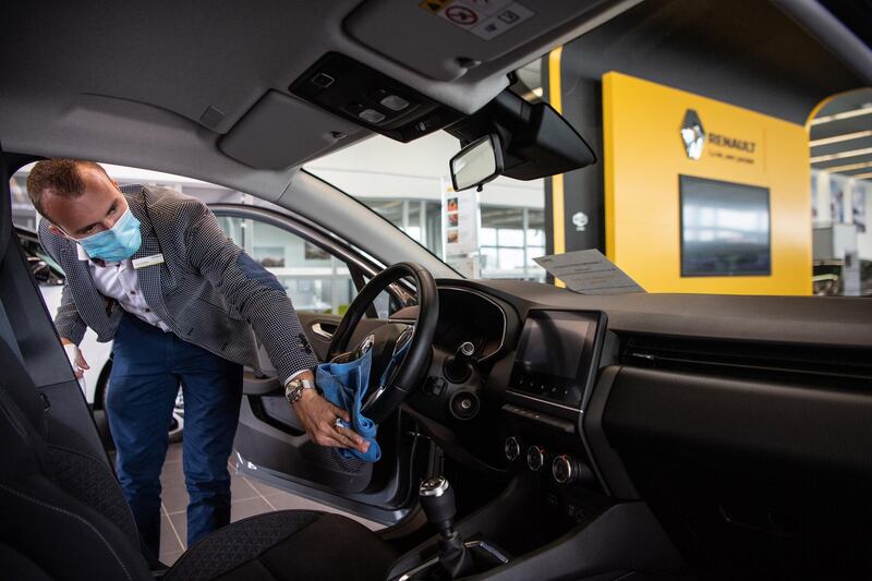 An employee wearing a protective face mask wipes the interior of a new automobile for a customer at a Renault SA showroom in Lille, France, on Tuesday, May 12, 2020. France plans to attach strings to any injection of public money into its crisis-hit automotive industry, with the repatriation of manufacturing a top priority. Photographer: Laurel Chor/Bloomberg via Getty Images