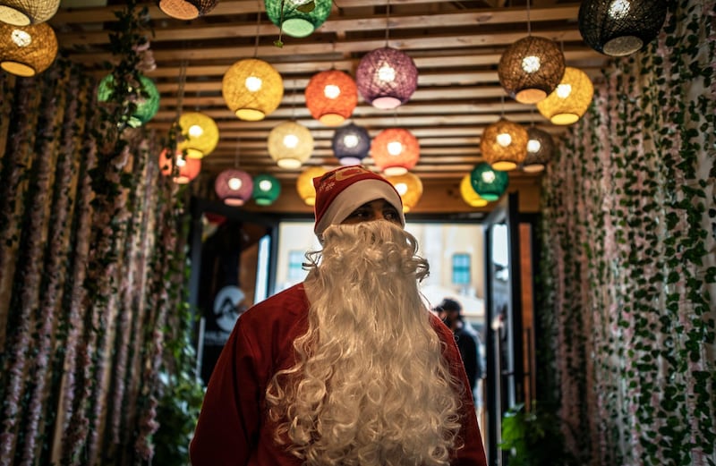 A Palestinian waiter dressed as Santa Claus welcomes visitors at the entrance of a restaurant on the beach in Gaza City. AP