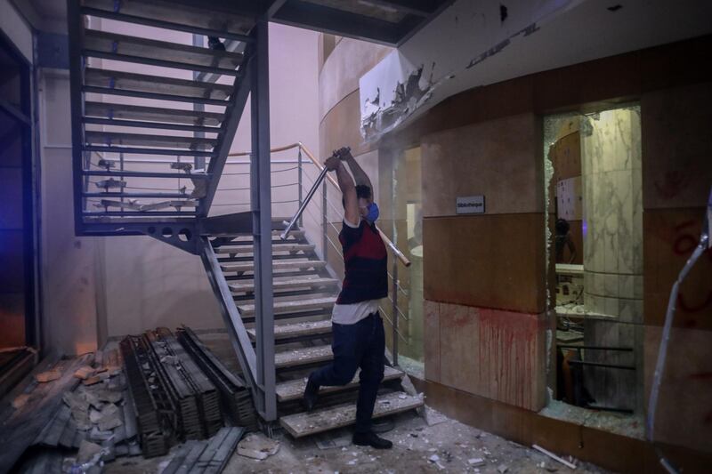 A protester strikes a wall with a metal bar inside the Lebanese Banks Association (ABL) headquarters. Bloomberg