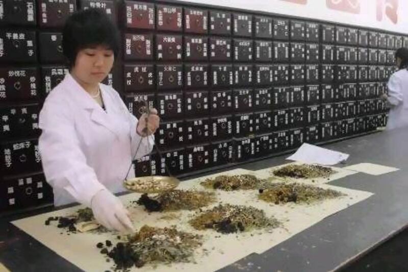A worker at a clinic in Beijing weighs ingredients for a traditional Chinese remedy.