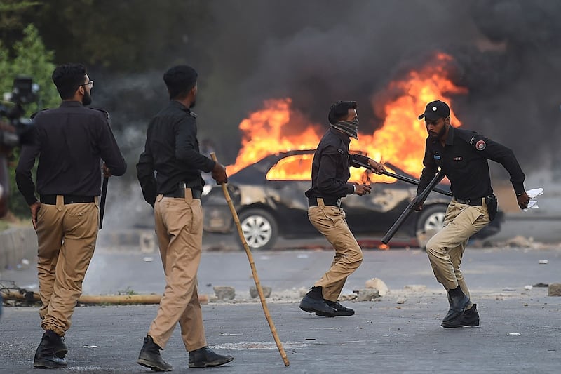 Policemen retreat after firing tear gas shells towards supporters of Mr Khan protesting against his arrest in Karachi. AFP