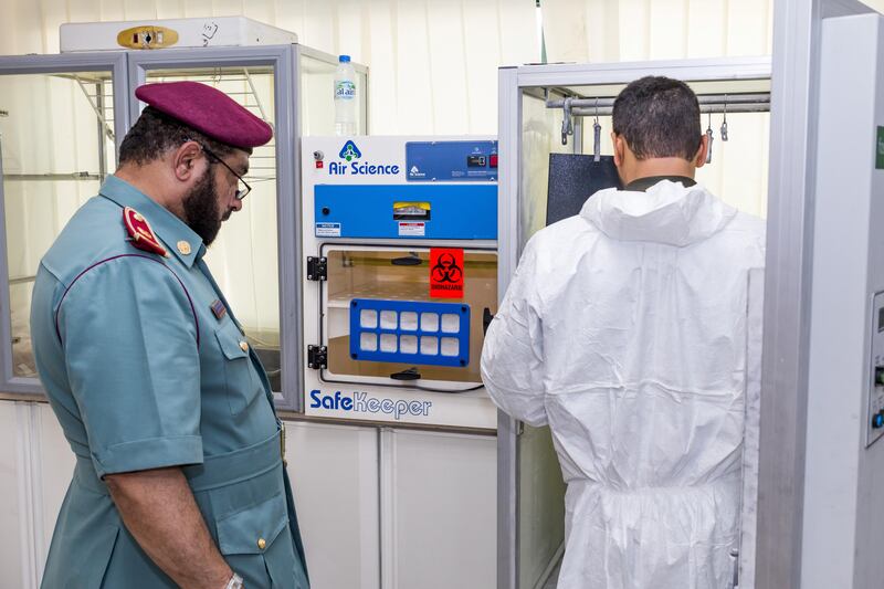 Ajman, UAE - September 05, 2017 - Mohd Hussain Waheedi of the Ajman Police Crime Scenes Investigative Unit stores new evidence in the crime lab as Police Chief Abdalla Yousif Mohd S. Alawadi looks on - Navin Khianey for The National