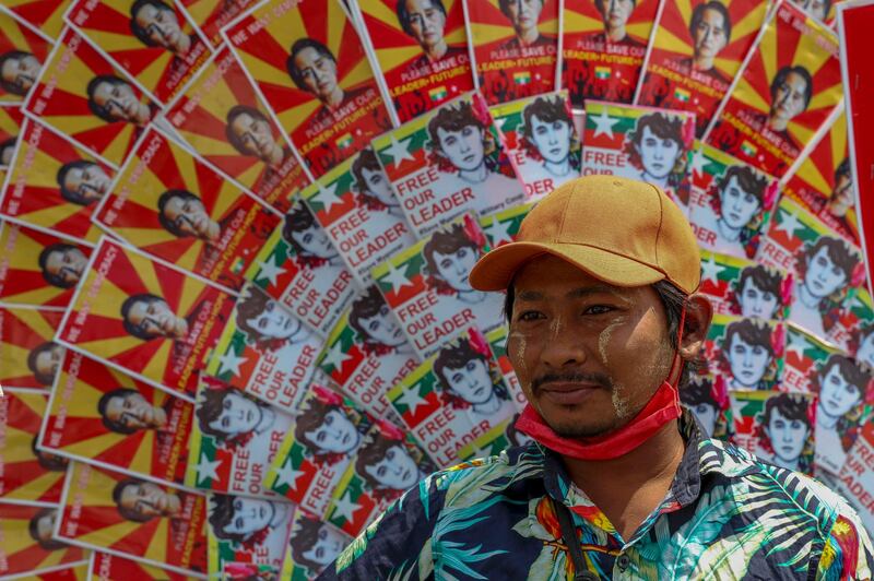 An anti-coup protester next to images of deposed Myanmar leader Aung San Suu Kyi during a street march in Mandalay, Myanmar. AP Photo