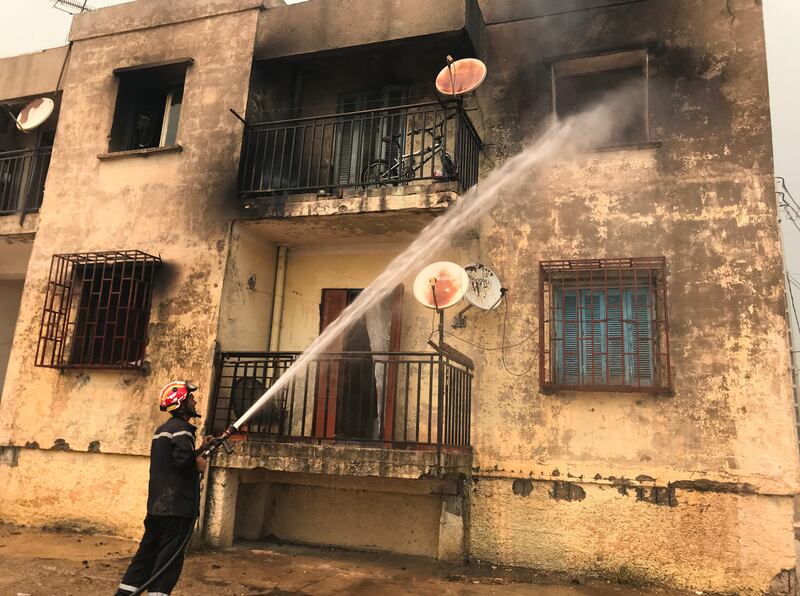 A firefighter damps down the remains of a house caught in the path of a wildfire in Ain Al Hammam, Tizi Ouzou.