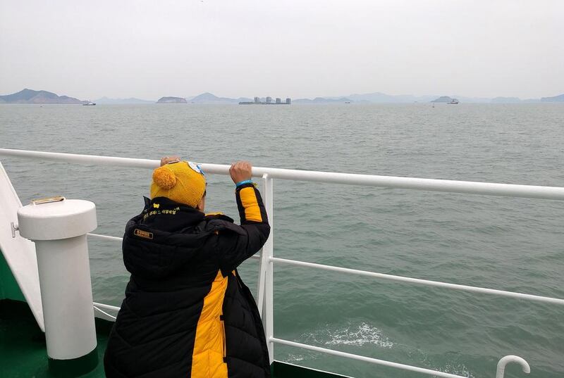 A relative of victim of the Sewol ferry disaster looking at the salvaging vessels, centre far, as they prepare to lift the wreck of the Sewol ferry out at sea on March 22, 2017 in Jindo-gun, South Korea. The Sewol sank off the Jindo Island in April 2014 killing more than 300 people, with nine still missing. Photo by Asan City via Getty Images