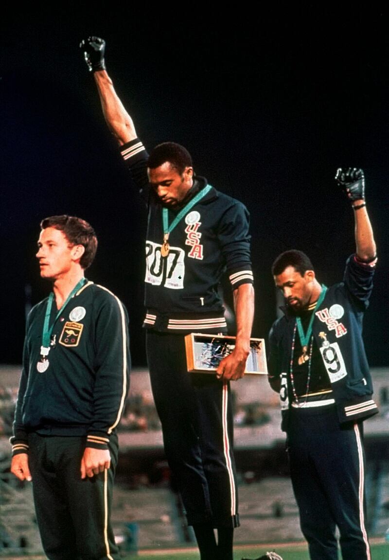 FILE - In this Oct. 16, 1968, file photo, U.S. athletes Tommie Smith, center, and John Carlos stare downward as they extend gloved hands skyward in during the playing of the "Star Spangled Banner" after Smith received the gold and Carlos the bronze for the 200 meter run at the Summer Olympic Games in Mexico City. Australian silver medalist Peter Norman is at left. When Smith and Carlos raised their fists 50 years ago at the Mexico City Olympics, they had a captive audience, back in the age when TV was king and the entire audience was rapt. A half-century later, many of the messages our athletes disseminate are every bit as powerful, but the audience is much more distracted.  (AP Photo/File)