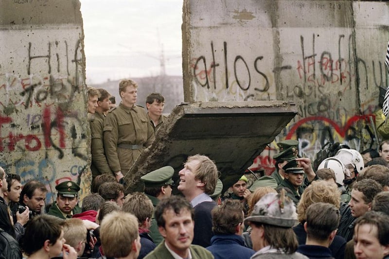 In 1989, West Berliners crowd in front of the Berlin Wall as they watch East German border guards demolish a section of the wall. (Gerard Malie / AFP)
