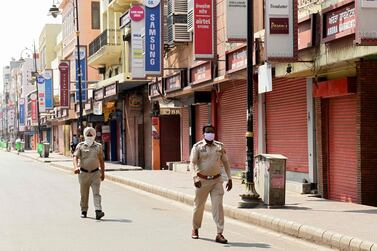 Police personnel patrol along a street during the weekend lockdown in Amritsar, Punjab. Economists say the impact of local lockdowns will not be as severe as last year. AFP 