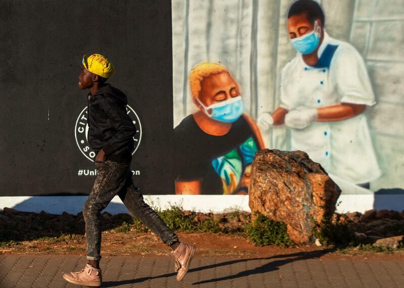 A young boy walks past a mural promoting vaccination for Covid-19 in Duduza township, east of Johannesburg, South Africa. AP Photo
